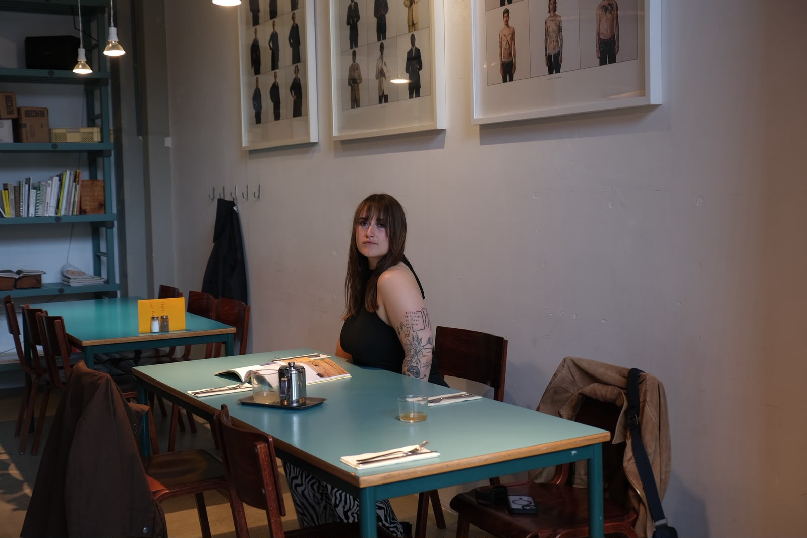 Nina Sophia zit aan een tafel in een caf&eacute; en kijkt in de camera