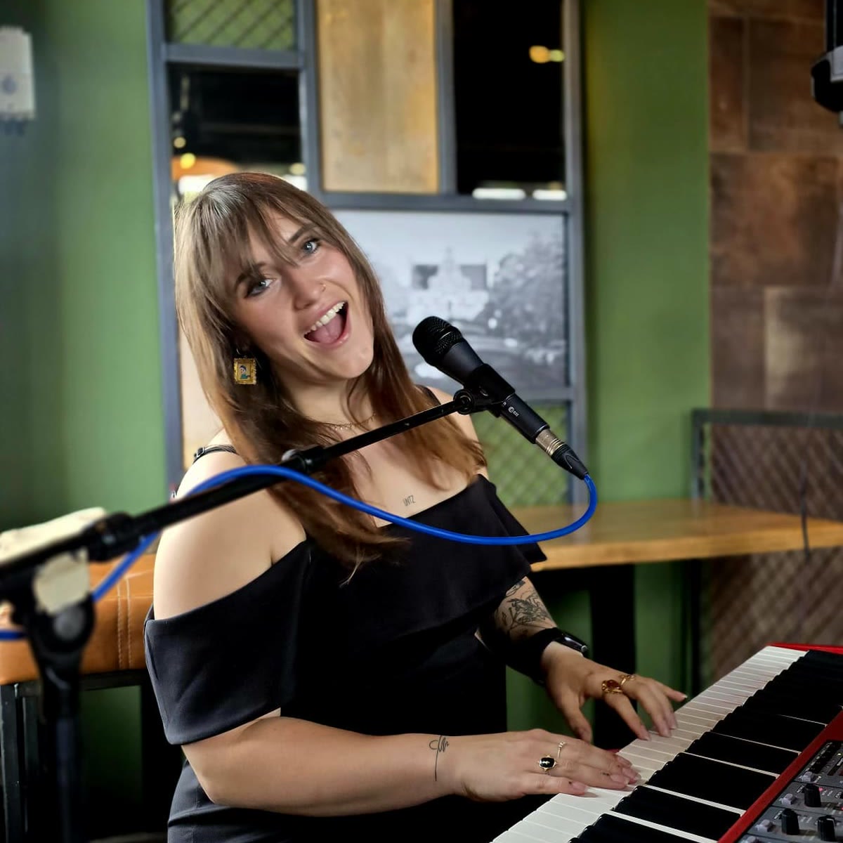 Nina zingt lachend achter haar keyboard tijdens een optreden