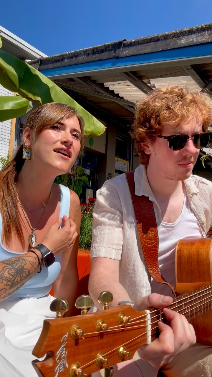 Nina zingt samen met een gitarist op een zonnig terras