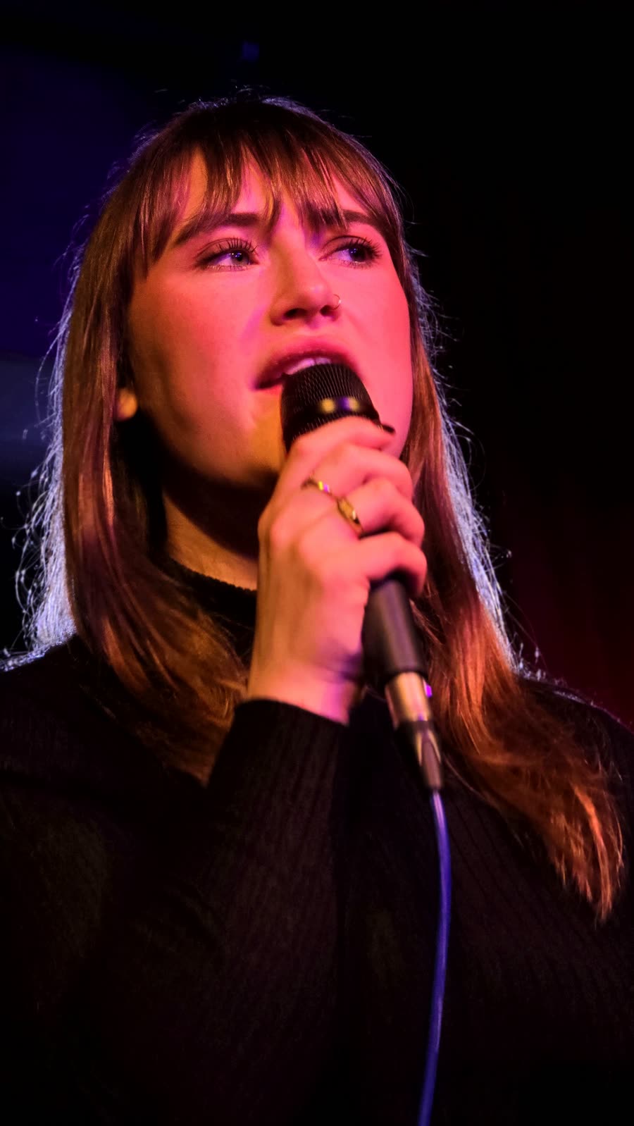 Nina Sophia zingt in de microfoon onder gekleurd podiumlicht