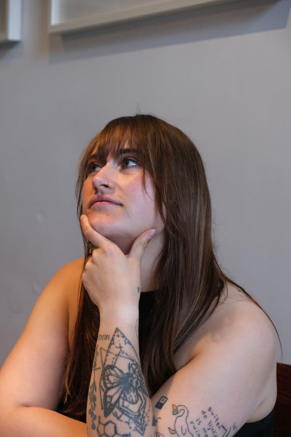 Portret van Nina Sophia, zittend en in gedachten, tegen een lichte achtergrond
